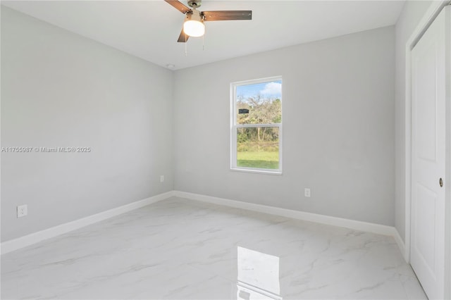 spare room featuring marble finish floor, baseboards, and a ceiling fan