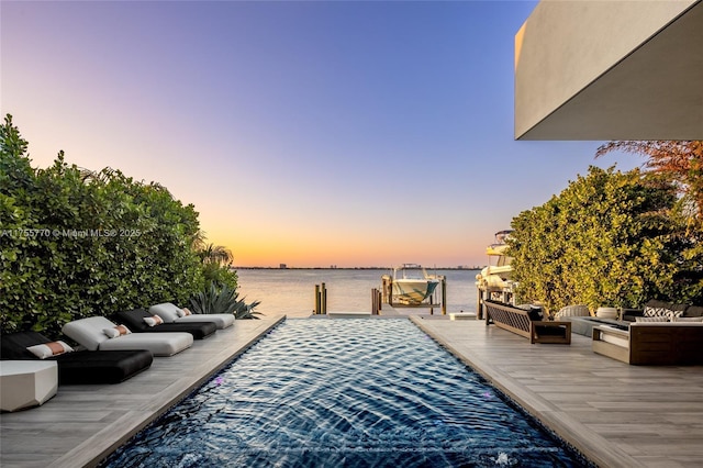view of swimming pool featuring a water view, outdoor lounge area, and a boat dock