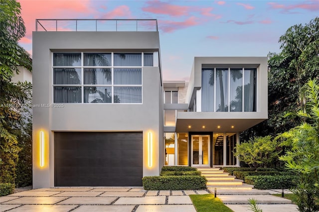modern home with a garage, stucco siding, french doors, and driveway