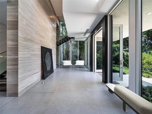 hallway featuring visible vents, floor to ceiling windows, and concrete flooring