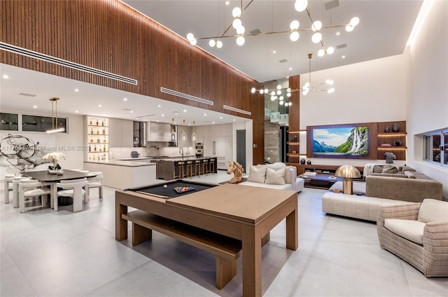 game room with an inviting chandelier, a sink, concrete floors, and a towering ceiling
