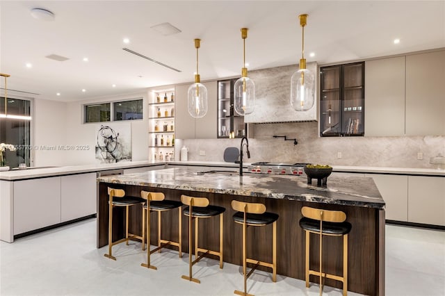 kitchen featuring decorative backsplash, modern cabinets, a breakfast bar, and a kitchen island with sink