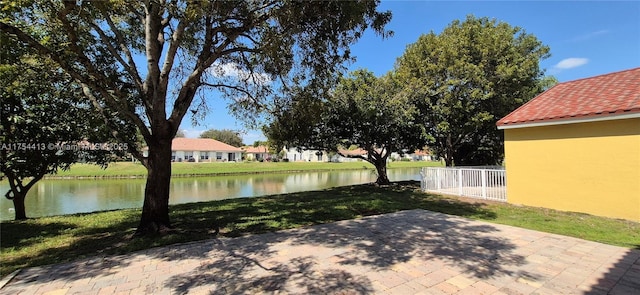 view of patio with a water view and fence