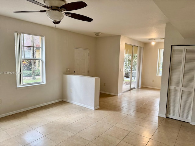 empty room featuring light tile patterned floors, ceiling fan, and baseboards