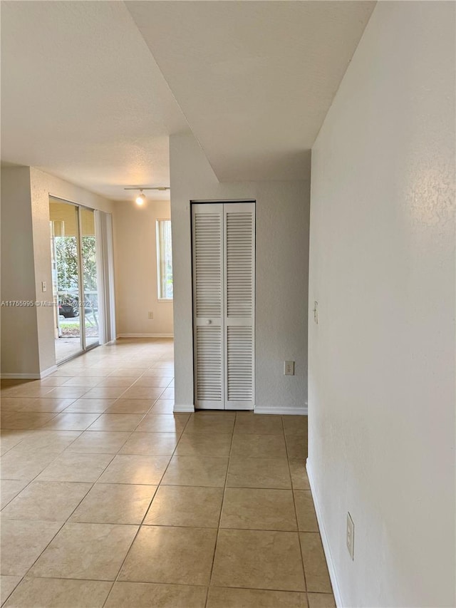 unfurnished bedroom featuring access to outside, baseboards, a closet, and light tile patterned flooring