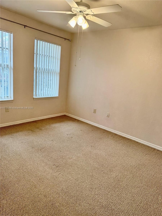 empty room with carpet floors, baseboards, and a ceiling fan