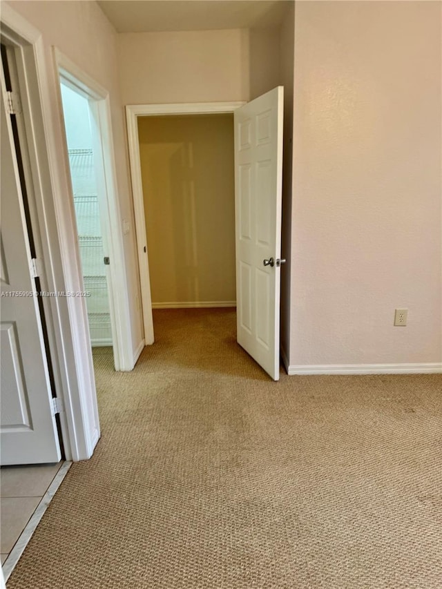 hallway with light colored carpet and baseboards