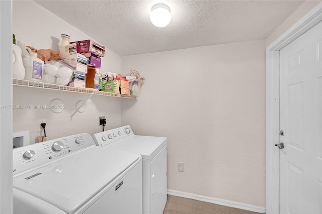 clothes washing area with laundry area, baseboards, washer and clothes dryer, and a textured ceiling