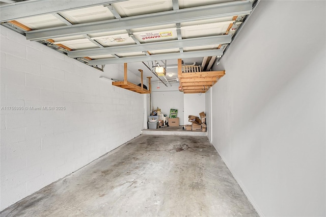 garage featuring concrete block wall and a garage door opener