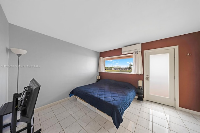 bedroom with light tile patterned floors, a wall unit AC, and baseboards