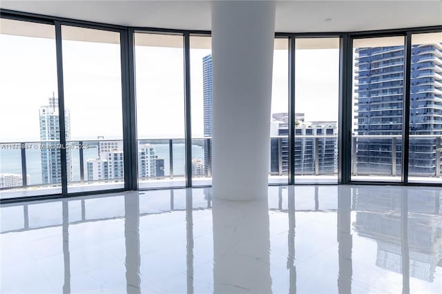 unfurnished room featuring a wall of windows, a city view, and plenty of natural light