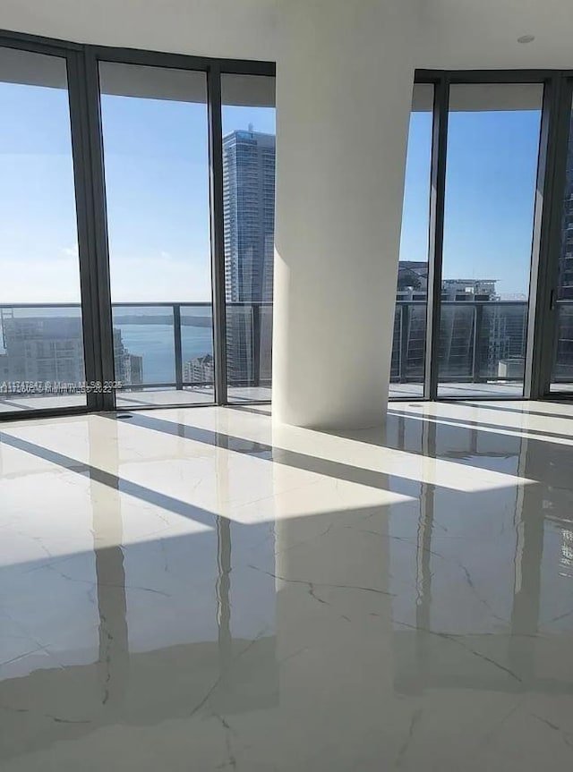 spare room with a water view and marble finish floor