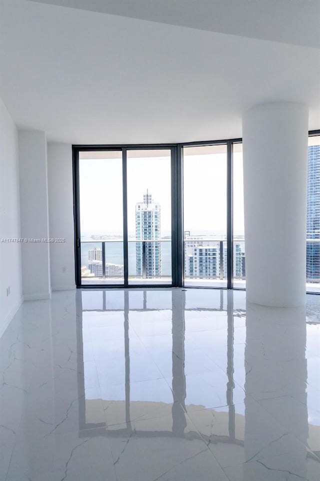 empty room with expansive windows, marble finish floor, and a city view