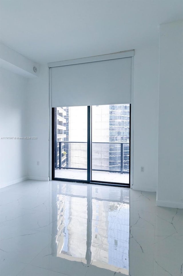 unfurnished room featuring marble finish floor and baseboards