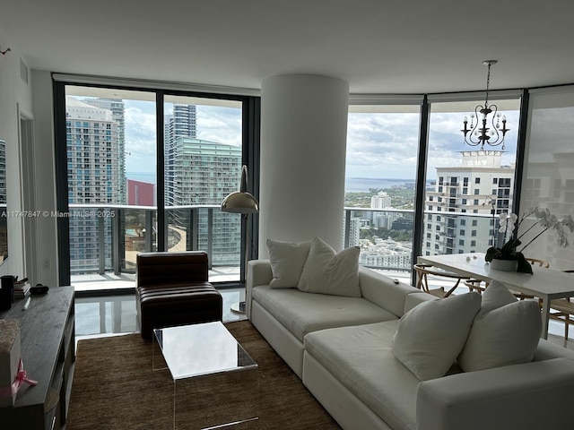 living area with an inviting chandelier, plenty of natural light, a view of city, and a wall of windows