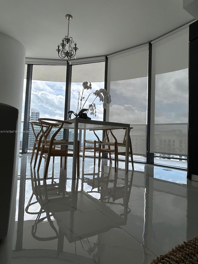 dining space featuring marble finish floor, a chandelier, and a wall of windows