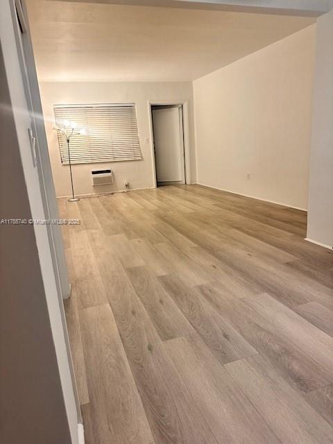 empty room with a wall mounted air conditioner and wood finished floors