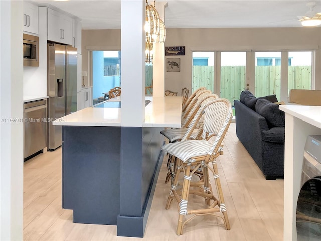 kitchen featuring a breakfast bar area, stainless steel appliances, washer / clothes dryer, light countertops, and a peninsula