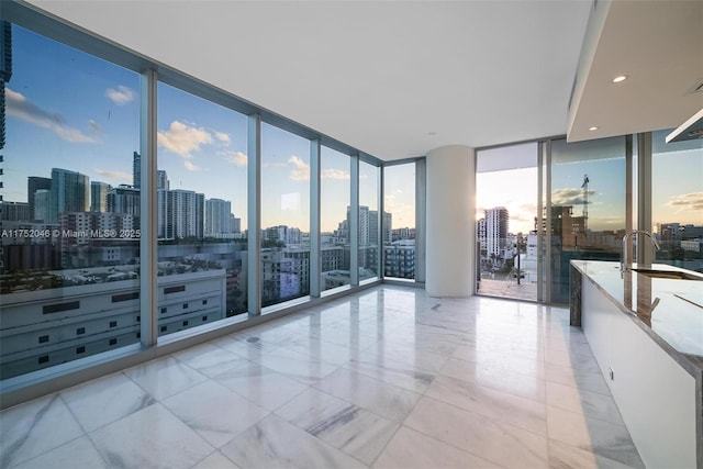 empty room featuring recessed lighting, a view of city, a wall of windows, and a sink