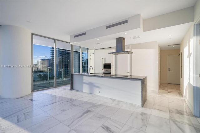 kitchen with visible vents, island exhaust hood, a sink, dark countertops, and white cabinets