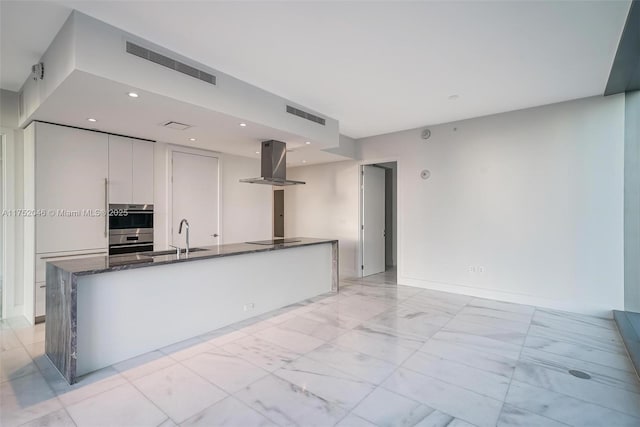 kitchen featuring black electric cooktop, island exhaust hood, visible vents, and a sink