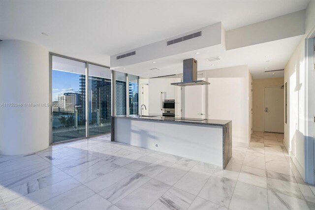 700 NE 26th Ter Unit 1105, Miami, FL 33137 - kitchen with island exhaust hood, expansive windows, white cabinets, a sink, and dark countertops