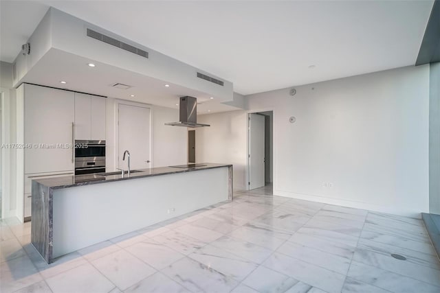 kitchen with visible vents, black electric stovetop, island range hood, marble finish floor, and a sink