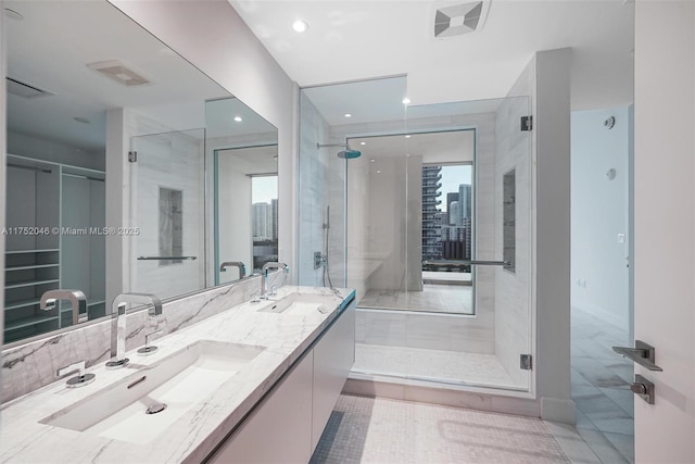 full bathroom featuring double vanity, a shower stall, a view of city, and a sink