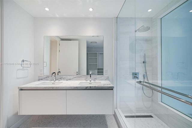 bathroom featuring double vanity, a stall shower, and a sink