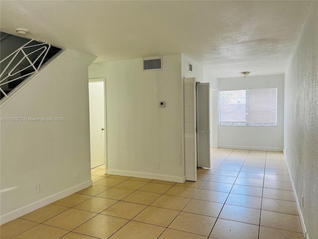 interior space featuring light tile patterned floors, baseboards, and visible vents