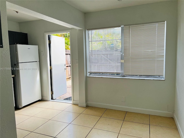 kitchen with light tile patterned floors, baseboards, and freestanding refrigerator