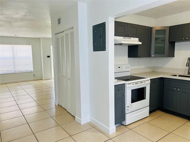 kitchen featuring light tile patterned floors, under cabinet range hood, white electric range, a sink, and electric panel