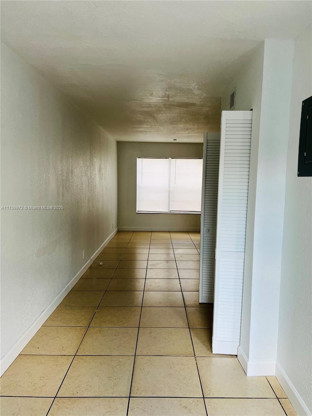 corridor featuring light tile patterned floors and baseboards