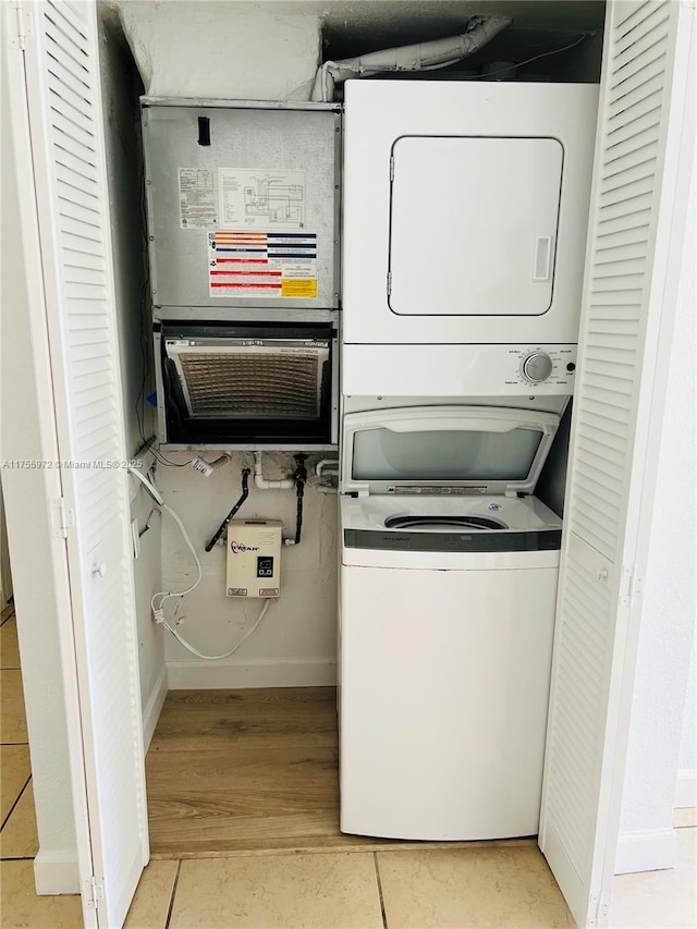 washroom featuring stacked washer / dryer, laundry area, and baseboards