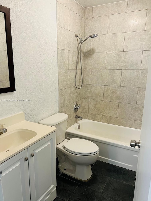 bathroom featuring a textured wall, tile patterned flooring, toilet, vanity, and washtub / shower combination