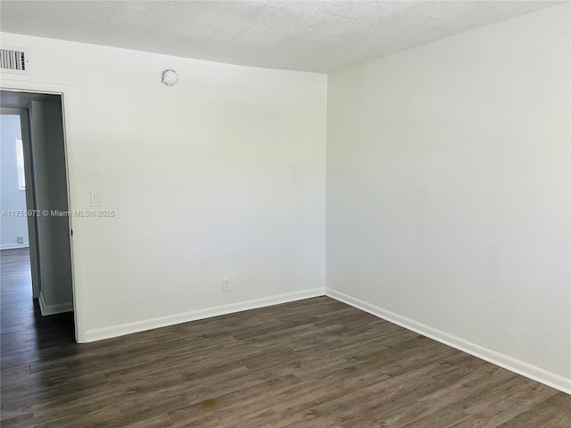 spare room featuring dark wood-type flooring and baseboards