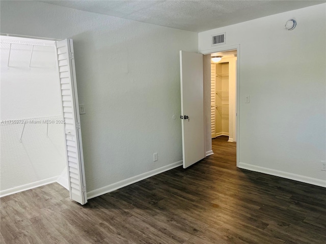 unfurnished bedroom featuring dark wood-style flooring, visible vents, and baseboards