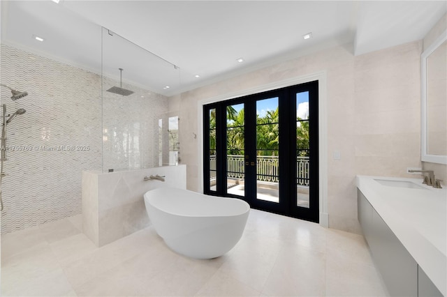 bathroom with a walk in shower, a freestanding tub, vanity, tile walls, and french doors