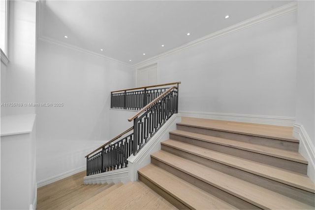 staircase featuring ornamental molding, baseboards, and wood finished floors