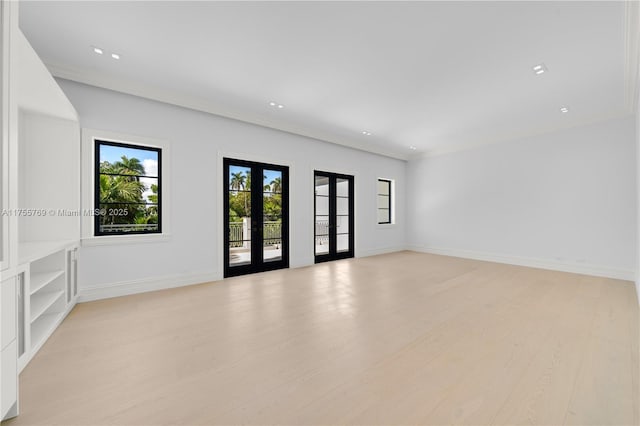 spare room with light wood-style floors, french doors, and baseboards