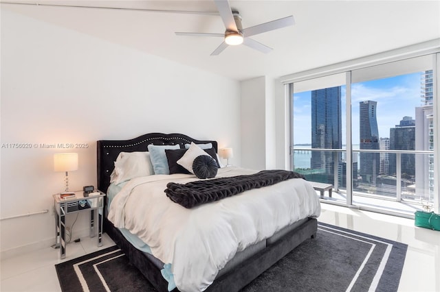 tiled bedroom with a view of city, a ceiling fan, a wall of windows, access to outside, and baseboards