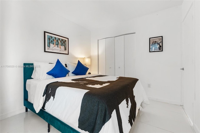 tiled bedroom featuring baseboards and a closet