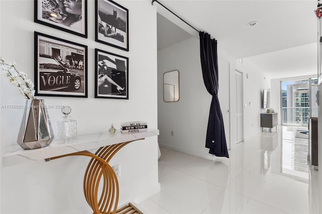 hall featuring baseboards and light tile patterned floors