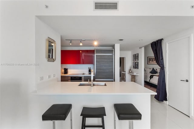 kitchen featuring visible vents, oven, a peninsula, a sink, and built in fridge