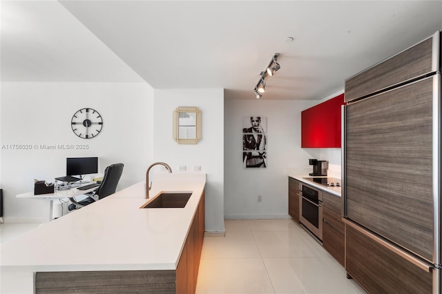 kitchen with oven, black electric cooktop, built in refrigerator, a sink, and light countertops