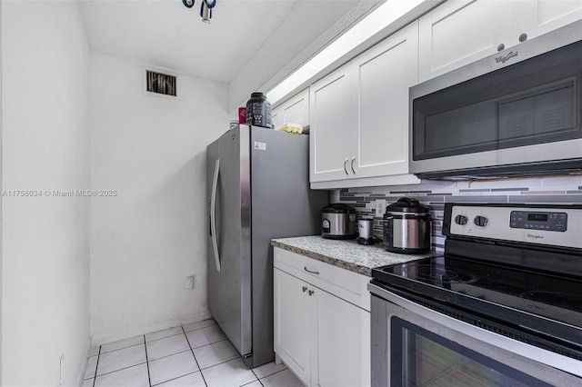 kitchen featuring stainless steel appliances, light tile patterned flooring, visible vents, and white cabinets