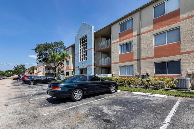 view of building exterior with central air condition unit and uncovered parking