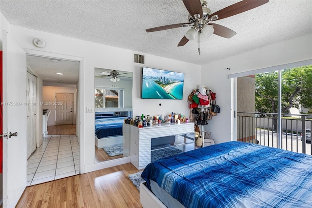 bedroom with access to exterior, visible vents, ceiling fan, a textured ceiling, and wood finished floors