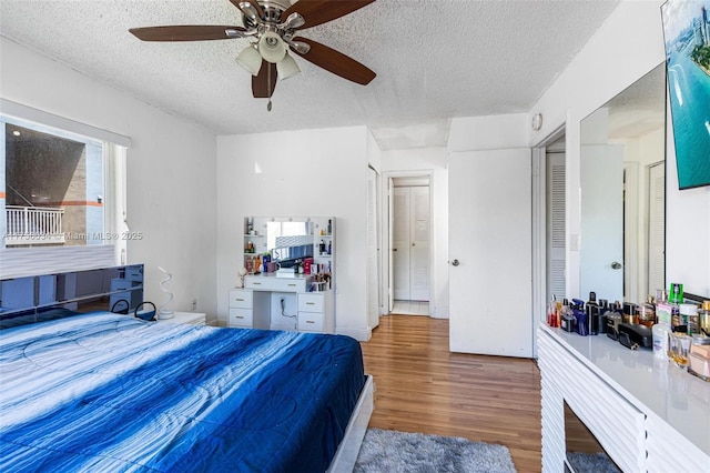 bedroom with ceiling fan, a textured ceiling, and wood finished floors