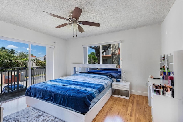 bedroom with baseboards, ceiling fan, wood finished floors, access to exterior, and a textured ceiling